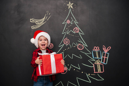 快乐的孩子抱着圣诞树绘图在 blackboa 附近的礼物