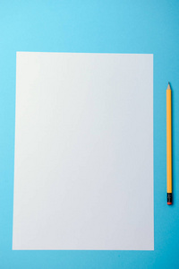 张空白的纸和黄色铅笔在蓝色背景上。从上面查看
