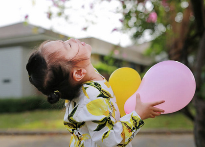 可爱的小女孩拿着气球在公园里, 微笑和乐趣