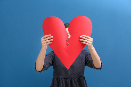 少妇撕毁纸心脏在颜色背景的一半.关系问题照片