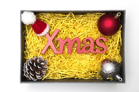 带黄色包装材料的黑色礼品盒中的 X mas 文本和毛皮帽球松木锥