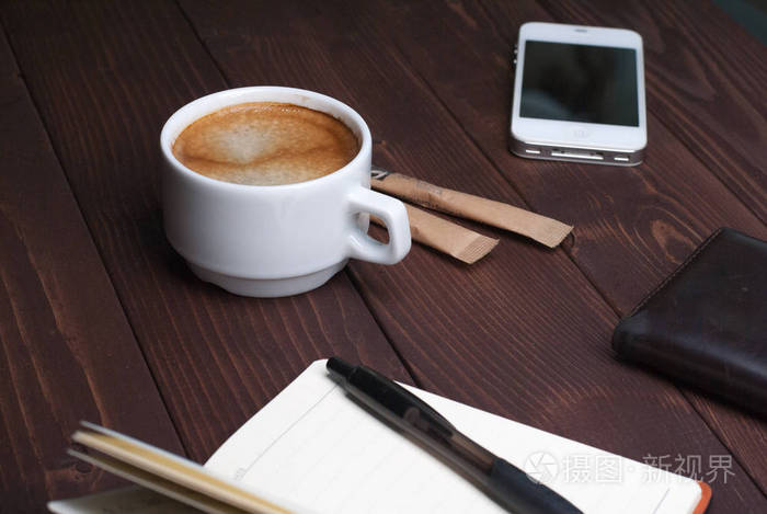 智能手机与笔记本和杯浓咖啡木背景