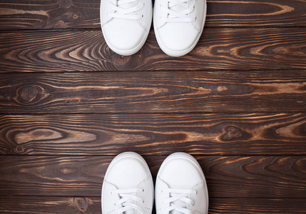 一双白色的帆布鞋在木制的。棕色背景白色运动鞋
