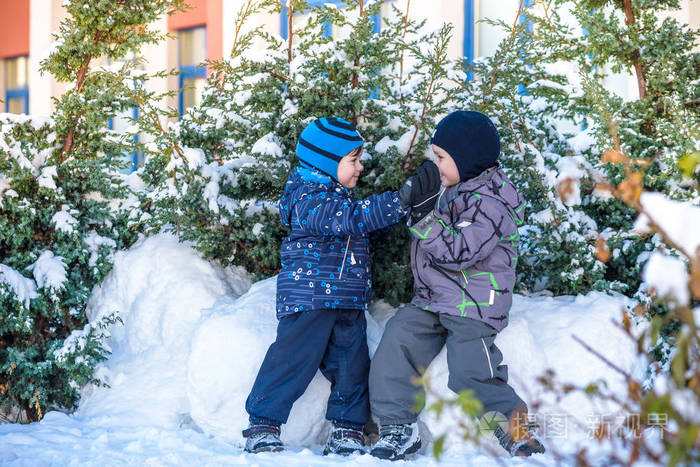两个小家伙男孩在颜色鲜艳的衣服在降雪期间在户外玩.