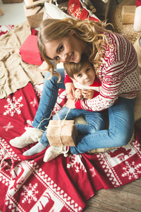 幸福的母亲和儿子的肖像在圣诞树的背景下, 在新年的房间。明信片的想法