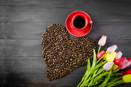 咖啡杯和散落在深木背景的咖啡粒心的形式。花束的郁金香和咖啡宣言的爱。复制空间。情人节概念
