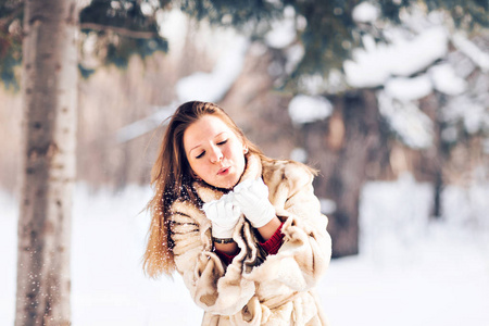 年轻漂亮的女人在冬天吹雪