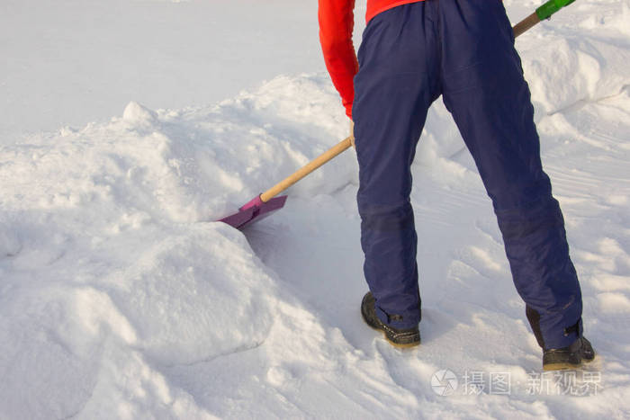 一个人用铲子清除积雪。冬天.寒冷的天气。乡间别墅的生活
