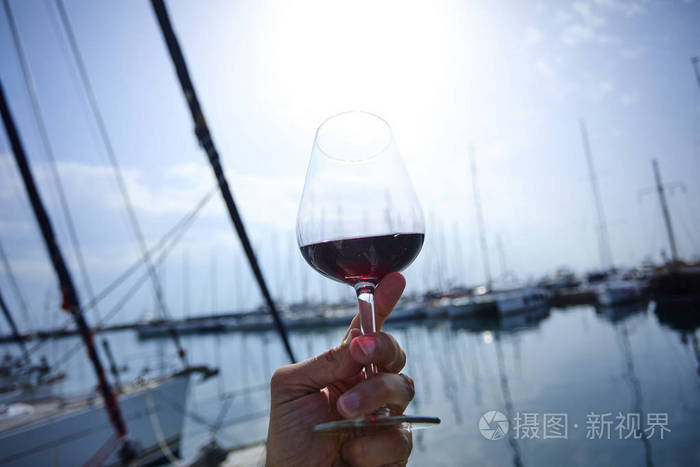 男士手捧红葡萄酒杯, 背景游艇