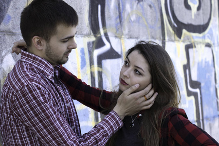 年轻的家伙抱着他的女朋友在涂鸦墙附近。爱情故事。圣一天的故事