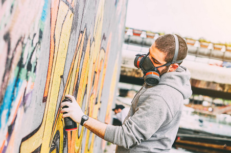 街头艺人在桥下的墙上画五颜六色的涂鸦都市人表演与 murales现代艺术的概念聚焦在他的手上