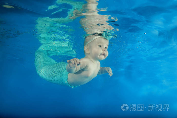一个穿着美人鱼服装的小女孩在水下游泳