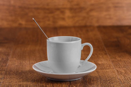 白色咖啡杯与汤匙在黑褐色木背景的白色茶托