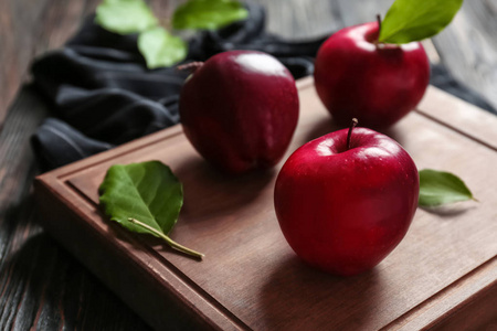木制板与成熟的红苹果和树叶在桌子上, 特写