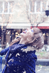 神奇的年轻女子在下雪的日子里玩得开心。女孩在外面吃雪花。圣诞节时间