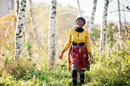 非洲裔美国女孩看黄色和红色的衣服，在金色的秋天 f