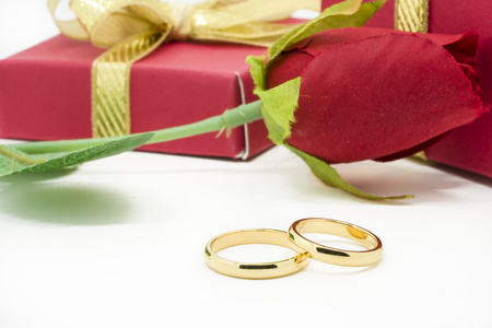 结婚戒指和白色背景上的人工玫瑰