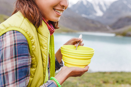 在山湖附近的一碗热汤享用晚餐的妇女远足者