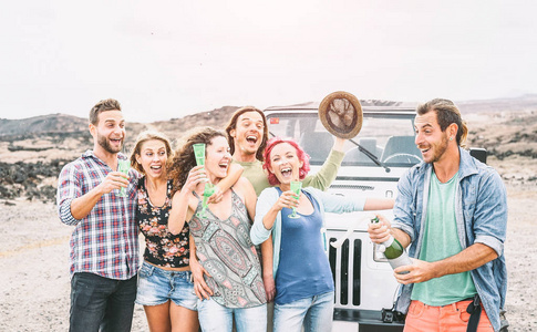 一群快乐的朋友在沙漠旅行的人有乐趣喝香槟普罗塞克在旅途中与吉普车友谊, 假期, 假日生活方式概念