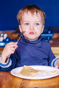 幼儿男孩在一家咖啡馆吃煎饼图片