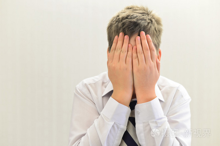抑郁的少年男孩用他的双手捂住了脸