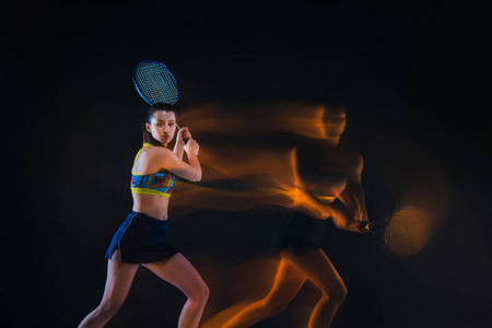 美丽的女孩网球运动员用球拍在深色背景上的肖像