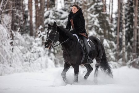 冬天森林里骑着黑马穿过雪地的女孩背景