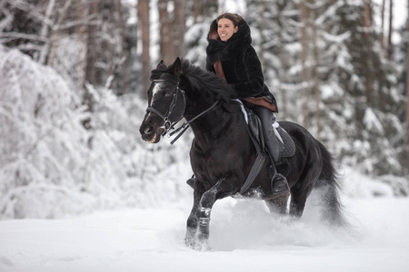 冬天森林里骑着黑马穿过雪地的女孩背景