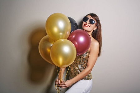 Waistup 的肖像美丽的年轻女子手持一束五颜六色的气球在手, 看着相机与露的微笑, 工作室拍摄