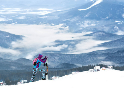 女孩滑雪板站在山坡上的高山上