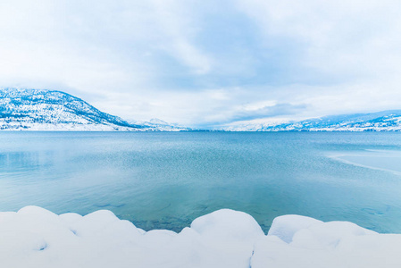 暴风雪后冬季冰雪覆盖的海岸线上根湖和山上的背景