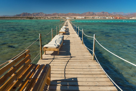 与贵妃椅在海水中度假村的码头。暑假。查看在与绿松石的水清澈的海水。暑假在海，海岸线在异国