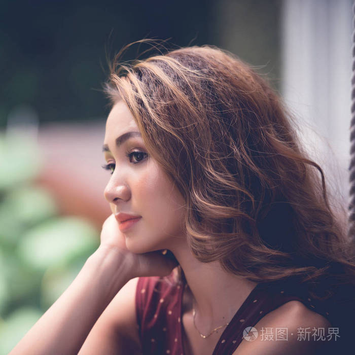 沉思漂亮的越南年轻女子坐在户外