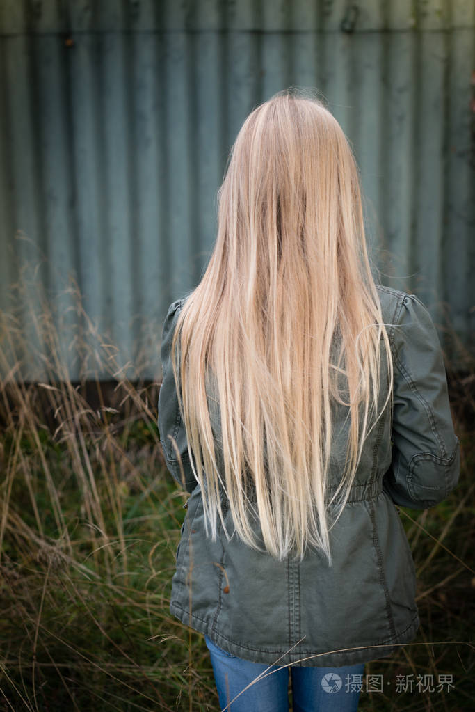 长着金色长发的女孩, 身后是一堵生锈的绿墙