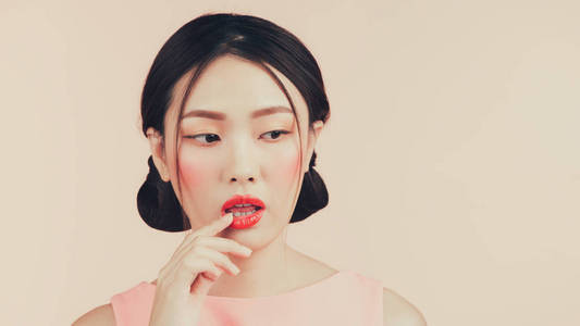 美丽的亚洲女孩与专业化妆和时尚的发型孤立粉红色。化妆品和化妆