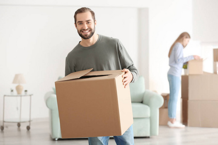 在新家的房间里搬箱子的年轻人照片