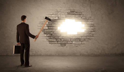 商人用锤子击打砖墙和开孔照片