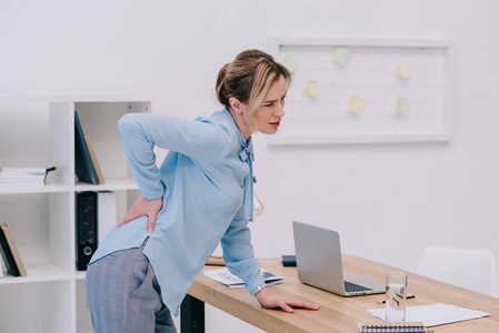 过度劳累的成年女商人在办公室 backpain