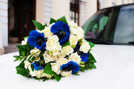 在白色汽车引擎盖上的美丽新娘花束