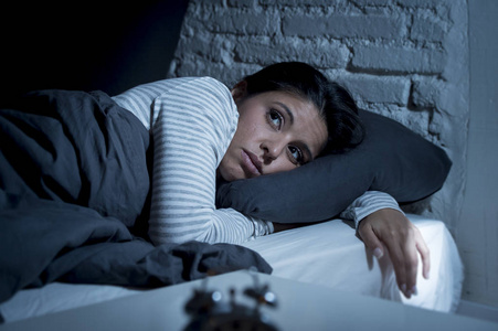 西班牙裔女人在家里卧室躺在床上,晚上很晚才入睡痛苦失眠照片