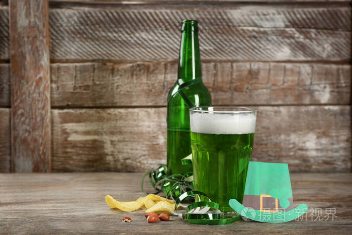 木桌上的一瓶一杯绿色啤酒圣帕特里克日庆典