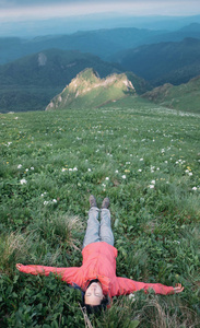 快乐的旅行者躺在山草甸上