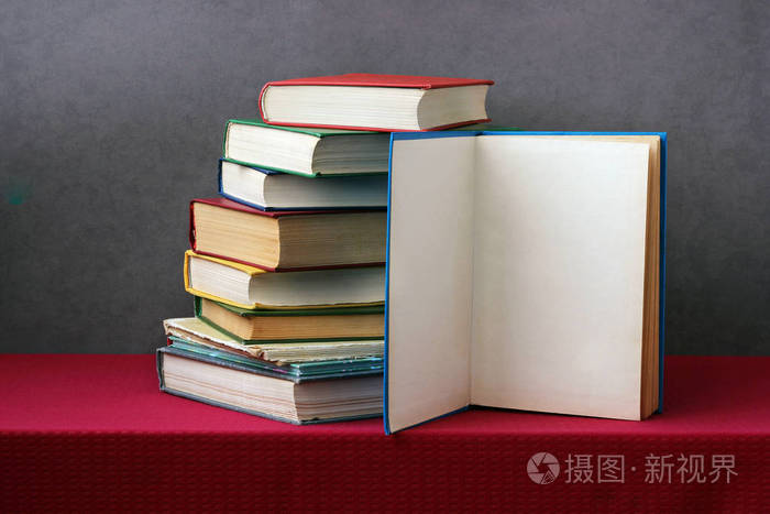 一摞书在桌子上,打开一本书