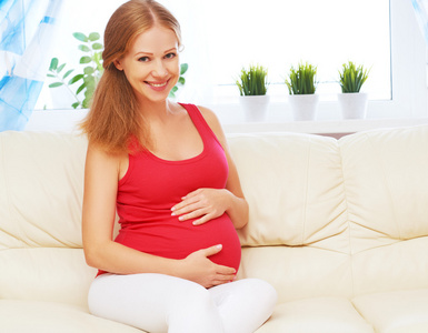 快乐的孕妇在家休息，坐在沙发上