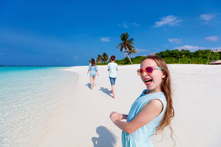 快乐的女孩和她的家人享受热带海滩假期照片