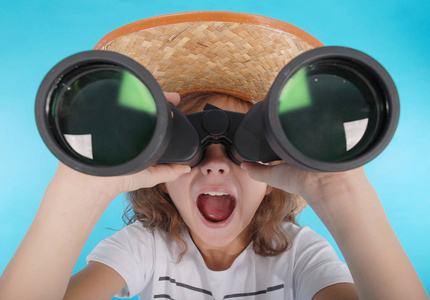 年轻漂亮的女孩,通过双筒望远镜与惊讶的表情看起来照片