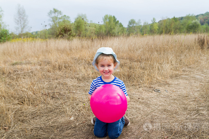 一个小女孩正坐在一起一个粉色的球