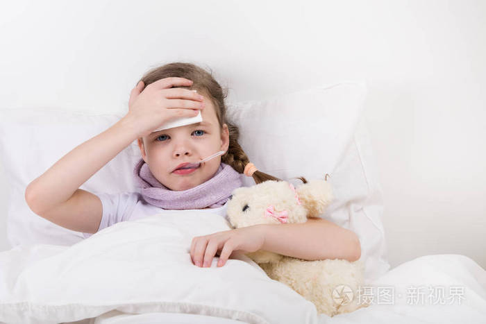 小女孩病倒了, 发烧了, 她把手伸到病头上, 抱着玩具狗.