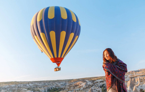 山顶上的一个旅游女孩, 享受着日出和气球的美景。愉快的旅行在土耳其概念