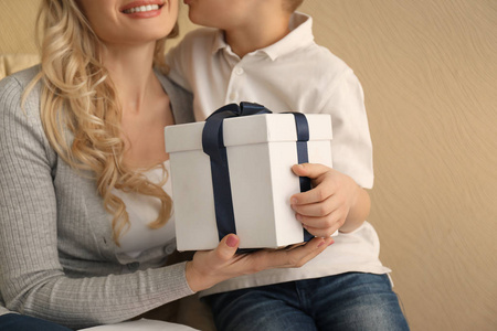 小男孩和他的母亲与礼物盒在颜色背景